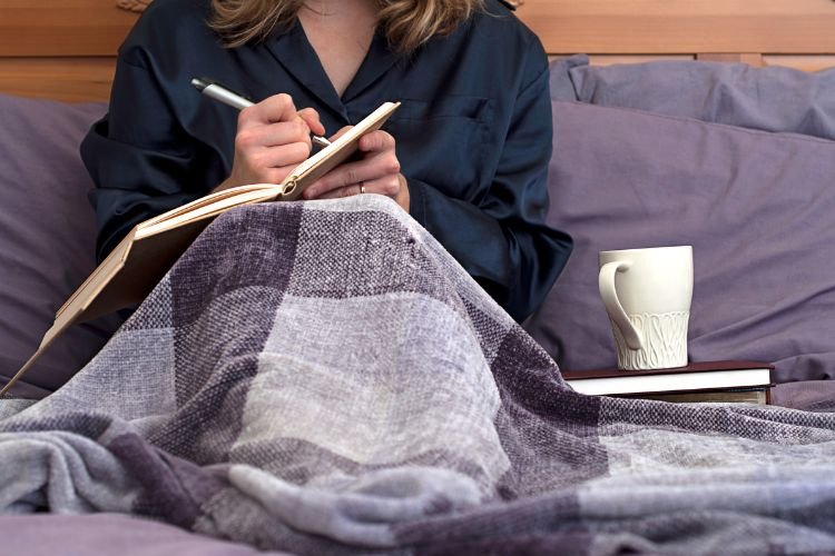 A woman journals as a practice she learned from wedding wellness tips for brides.