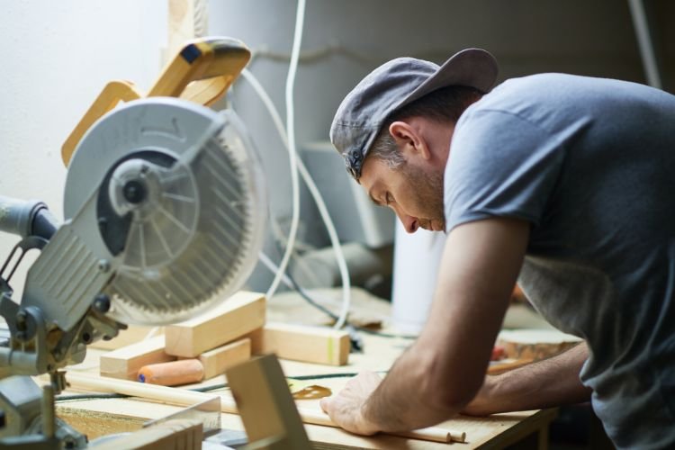 A man is enthralled in his woodworking. An important part of wedding wellness for grooms is making time for hobbies.