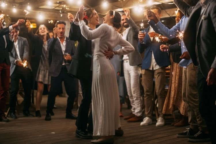 A same-sex couple dancing for their first dance at their wedding, surrounded by family and loved ones.