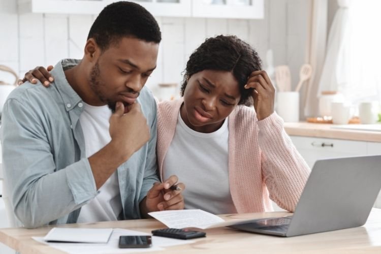 A couple stresses over a laptop and plans; this stress can be alleviated by hiring a day of wedding coordinator near you.